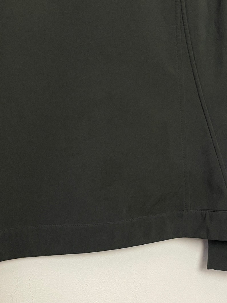 May include: A dark green jacket with a zipper closure and a seam down the back.