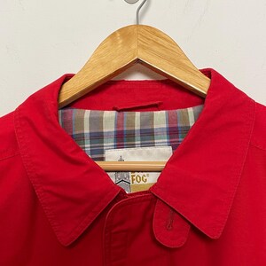 Peut inclure: Une veste rouge avec une doublure &agrave; carreaux et un logo "Fog" dor&eacute; sur le col.