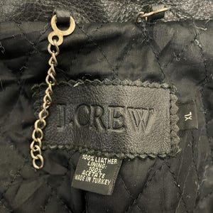 May include: A black leather jacket with a J.Crew label. The label says "100% Leather Lining: 100% Acetate Made in Turkey".