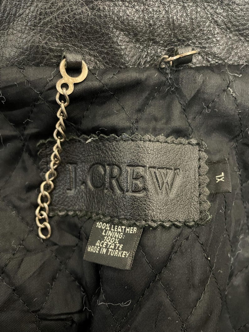 May include: A black leather jacket with a J.Crew label. The label says "100% Leather Lining: 100% Acetate Made in Turkey".