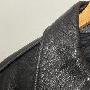 May include: Close-up of a black leather jacket collar. The leather has a textured, pebbled surface.