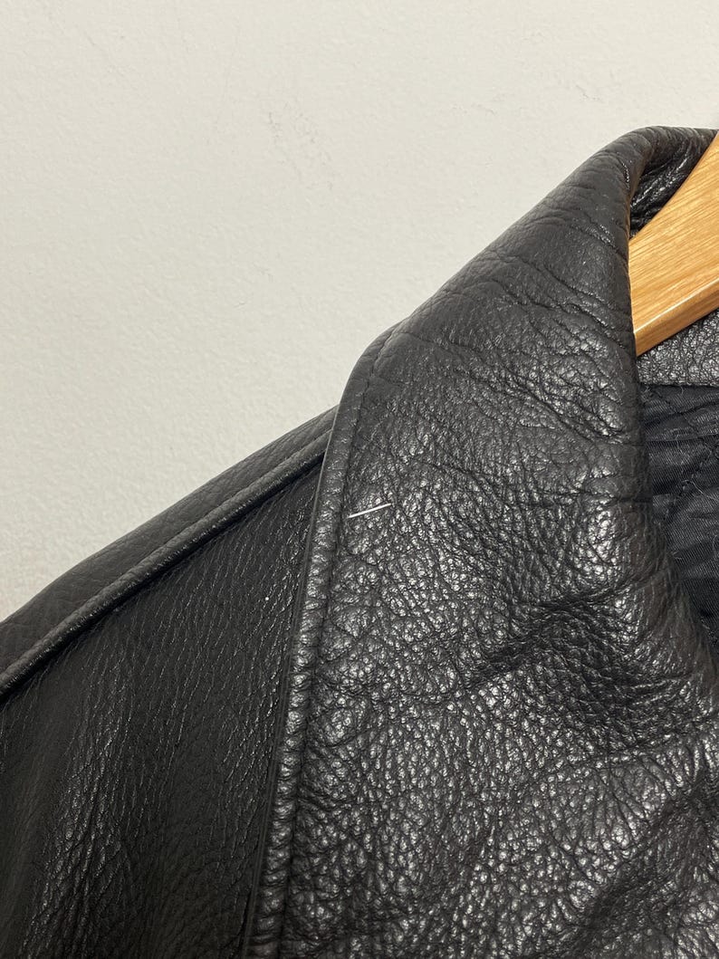 May include: Close-up of a black leather jacket collar. The leather has a textured, pebbled surface.