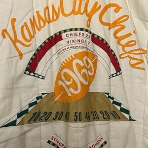 May include: Cream fabric with orange text reading "Kansas City Chiefs." The image commemorates Super Bowl IV, with the score Chiefs 23, Vikings 7, and the year 1969. Includes a football graphic and yard lines.