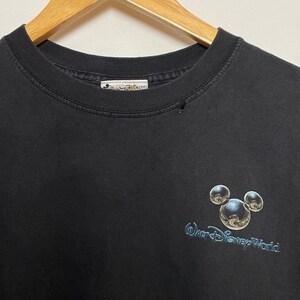 May include: Black t-shirt with a silver Mickey Mouse head and the text "Walt Disney World" in a silver font.