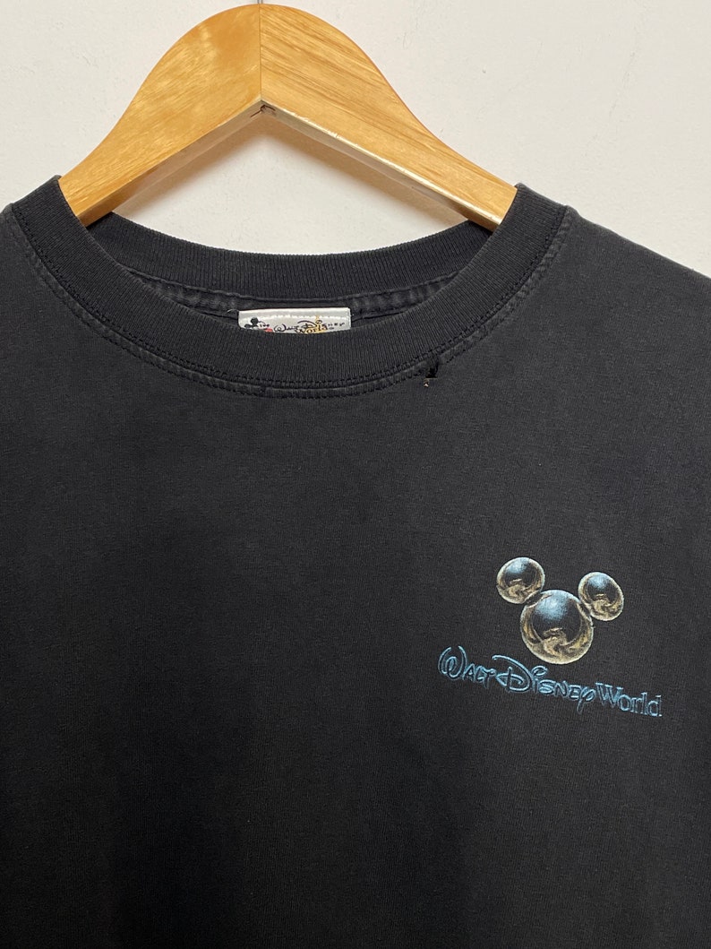 May include: Black t-shirt with a silver Mickey Mouse head and the text "Walt Disney World" in a silver font.