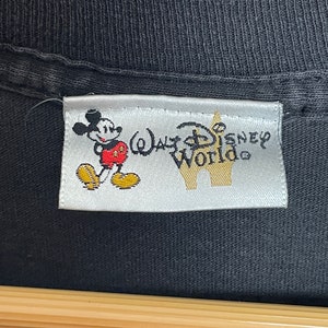 May include: A white tag with a black outline, featuring a cartoon image of Mickey Mouse and the text "Walt Disney World".