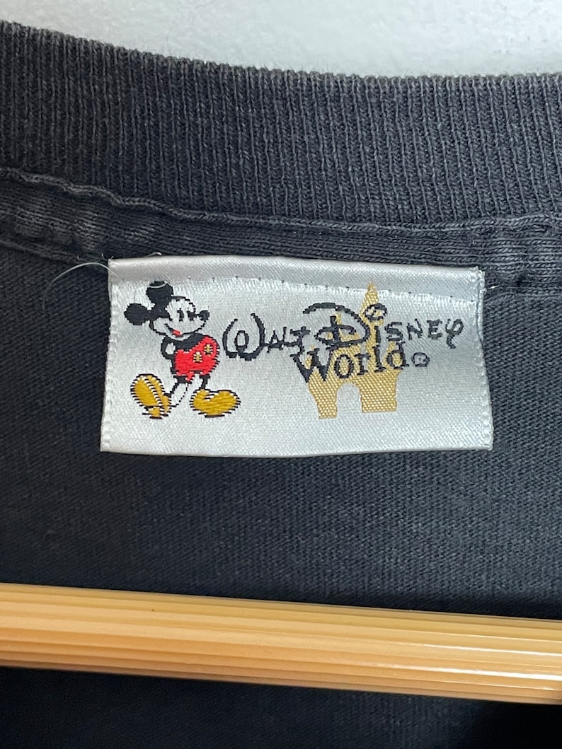 May include: A white tag with a black outline, featuring a cartoon image of Mickey Mouse and the text "Walt Disney World".