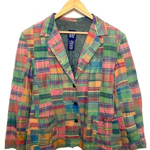 May include: A long-sleeve blazer featuring a multi-colored patchwork plaid pattern in shades of green, pink, blue, and orange. The garment has a notched lapel, three front buttons, and two lower pockets. A GAP brand label is visible at the neck.