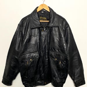 May include: Black leather bomber jacket with a zip fastening and a patch on the left chest that reads "Leather Soul Genuine Leather".