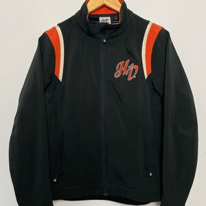 May include: Black zippered jacket with orange and white stripes on the sleeves and a Harley Davidson logo on the front.