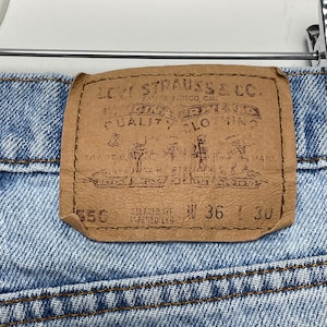 May include: Close-up of the back of blue denim jeans with a brown leather patch. The patch reads "LEVI STRAUSS & CO." and includes the text "QUALITY CLOTHING." The jeans are size W36 L30, relaxed fit, tapered leg.
