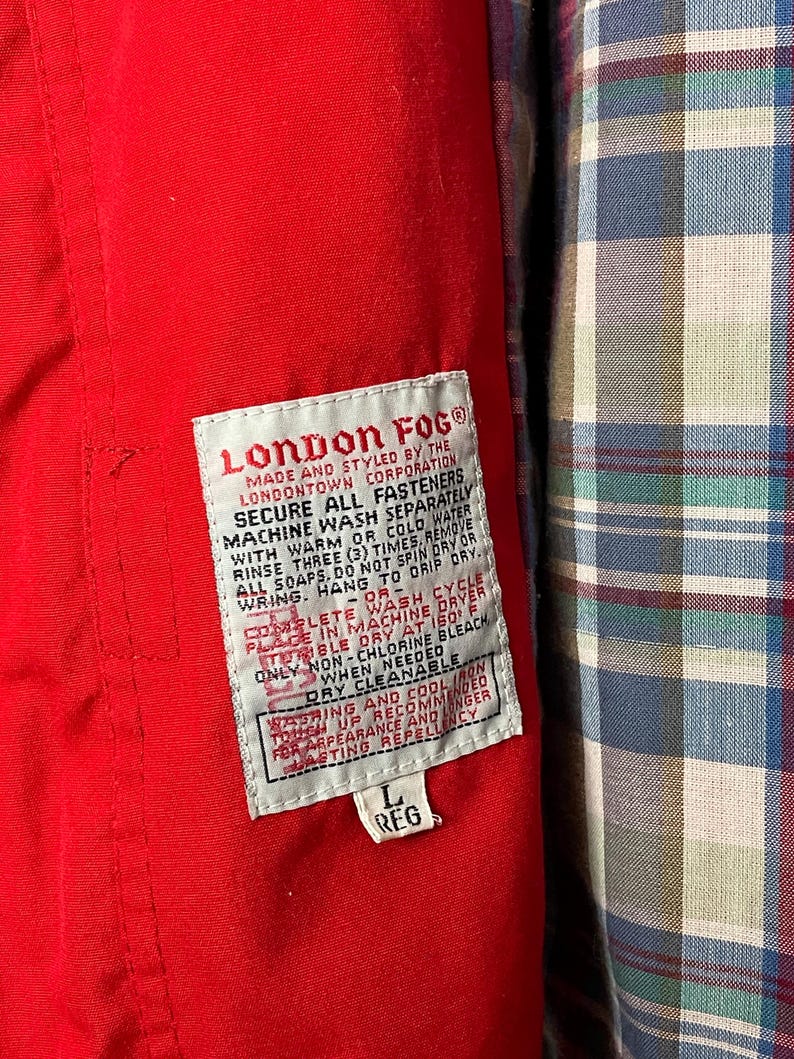 Peut inclure: Une &eacute;tiquette de veste rouge London Fog avec du texte blanc d&eacute;taillant les instructions d'entretien. L'&eacute;tiquette indique "London Fog", "Made and styled by the Londontown Corporation", "Secure all fasteners", "Machine wash separately with warm or cold water", "Rinse three (3) times. Remove all soaps. Do not spin dry or wring. Hang to drip dry.", "Complete wash cycle - or - Place in machine dryer tumble dry at 150 F", "Only non-chlorine bleach when needed", "Dry cleanable", "Washing and cool iron touch up recommended for appearance and longer lasting repellency", "L Reg".