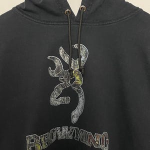 May include: Black hooded sweatshirt with a camouflage Browning logo and the word "Browning" in a stylized font.
