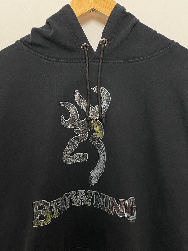 May include: Black hooded sweatshirt with a camouflage Browning logo and the word "Browning" in a stylized font.