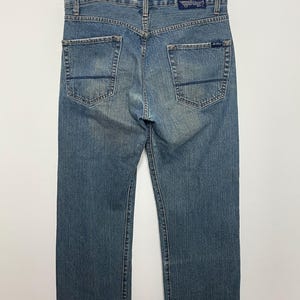 Op de afbeelding: Lichtblauwe denim jeans met een klassiek vijf-zakken ontwerp. De jeans hebben een rechte pijp en een vervaagde wassing. De achterkant heeft twee zakken en een leren patch met het merklogo. De jeans hangen aan een houten hanger.