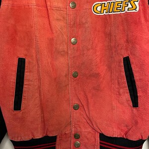 Puede incluir: Chaqueta bomber de cuero roja con pu&ntilde;os a rayas rojas y negras y un parche "CHIEFS" en blanco y negro en el pecho.
