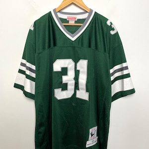 Pode incluir: Camisola de malha verde com o número 31 em branco na frente e atrás. A camisola tem detalhes brancos e cinzentos nas mangas e na gola. A camisola está pendurada num cabide de madeira.