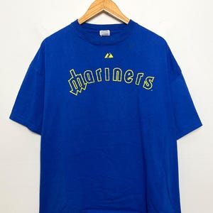 May include: A white ceramic mug with a black handle and the text "But First, Coffee" in a black, bold font. The mug is on a white surface.