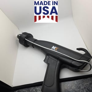 May include: Black handheld tool with a trigger and a curved handle. The tool has a metal wire extending from the front and the text "Made in USA" in a red, white, and blue design.