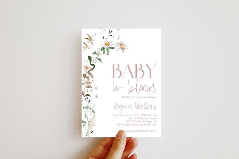 May include: A floral baby shower invitation with a watercolor design of white flowers and green leaves. The text reads "BABY in bloom" and includes the name "Regina Walters" and the date and time of the shower.