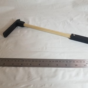 May include: A black and wood-toned tool with a ruler. The tool has a black handle and a wooden shaft. The ruler is made of metal and is 12 inches long.