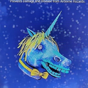 Op de afbeelding: Een blauw en geel eenhoornmasker met een strikje, een lange hoorn en een grijnzende mond. Het masker heeft de tekst "Fasnacht Glowing Unicorn Mask" en "Prevents Damage and Disease from Airborne Hazards."