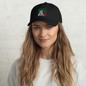 Peut inclure: Une casquette de baseball noire avec un motif brodé aux couleurs du drapeau des Émirats arabes unis. Le motif est une représentation stylisée du mot arabe pour "EAU".