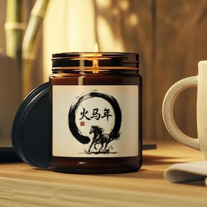 May include: A brown glass jar candle with a black lid. The label features a black circle with Chinese characters and a running horse illustration. The candle is on a wooden surface, with a white mug in the background.