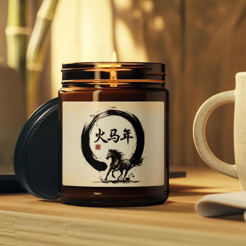 May include: A brown glass jar candle with a black lid. The label features a black circle with Chinese characters and a running horse illustration. The candle is on a wooden surface, with a white mug in the background.