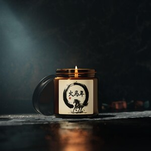 May include: A lit candle in a brown glass jar with a black lid. The label features a black circular design with Chinese characters and a running horse illustration. The candle is on a dark surface.