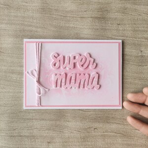 Delicada tarjeta en relieve para el Día de la Madre en color rosa con romántico fondo floral y adornada con un lazo a juego, Regalo mamá
