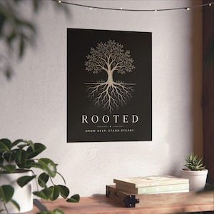 May include: A rectangular wall poster with a black background featuring a gold-toned line art illustration of a tree with visible roots. The text ROOTED is printed in white capital letters, followed by the text GROW DEEP. STAND STEADY.