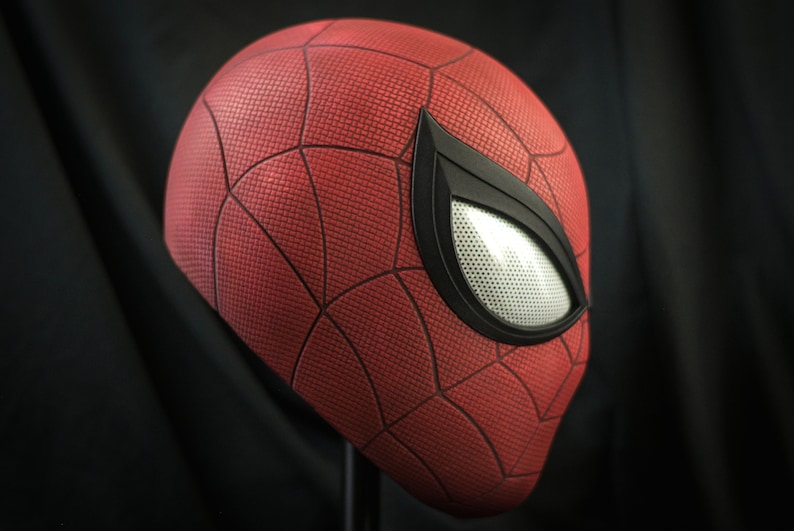 Puede incluir: Una m&aacute;scara de Spider-Man roja y negra con un patr&oacute;n de telara&ntilde;a detallado y una pieza de ojo negra con una malla blanca.