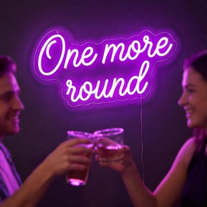May include: A neon sign in a purple hue displays the words "One more round" in a cursive font. Two people are seen toasting with glasses of a reddish-brown liquid. The background is a dark shade of purple.