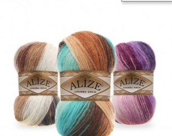 Puede incluir: Tres ovillos de hilo en diferentes combinaciones de colores. El hilo es una mezcla de angora y lana, y está en estilo batik. El hilo está etiquetado como "Alize Angora Gold Batik".