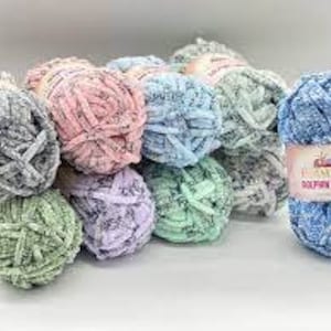 Puede incluir: Surtido de ovillos de lana de colores en varios tonos de azul, verde, rosa y gris. La lana es suave, peluda, de textura tipo chenilla. La etiqueta de un ovillo dice "Himalaya Dolphin Tweed."