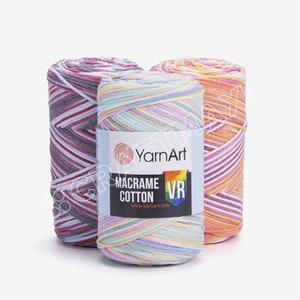 Könnte beinhalten: Drei Spulen mit buntem Garn für Makramee-Projekte. Das Garn ist eine Mischung aus Weiß und Pastellfarben, darunter Rosa, Blau, Gelb und Orange. Das Etikett lautet "YarnArt Macrame Cotton VR www.yarnart.info"