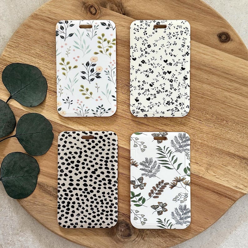 Puede incluir: Cuatro etiquetas de equipaje blancas con diferentes patrones. Una etiqueta tiene un dise&ntilde;o floral con acentos rosas y verdes. Otra tiene un patr&oacute;n floral en blanco y negro. Una tercera tiene un estampado d&aacute;lmata. La &uacute;ltima tiene un dise&ntilde;o bot&aacute;nico con mariposas.