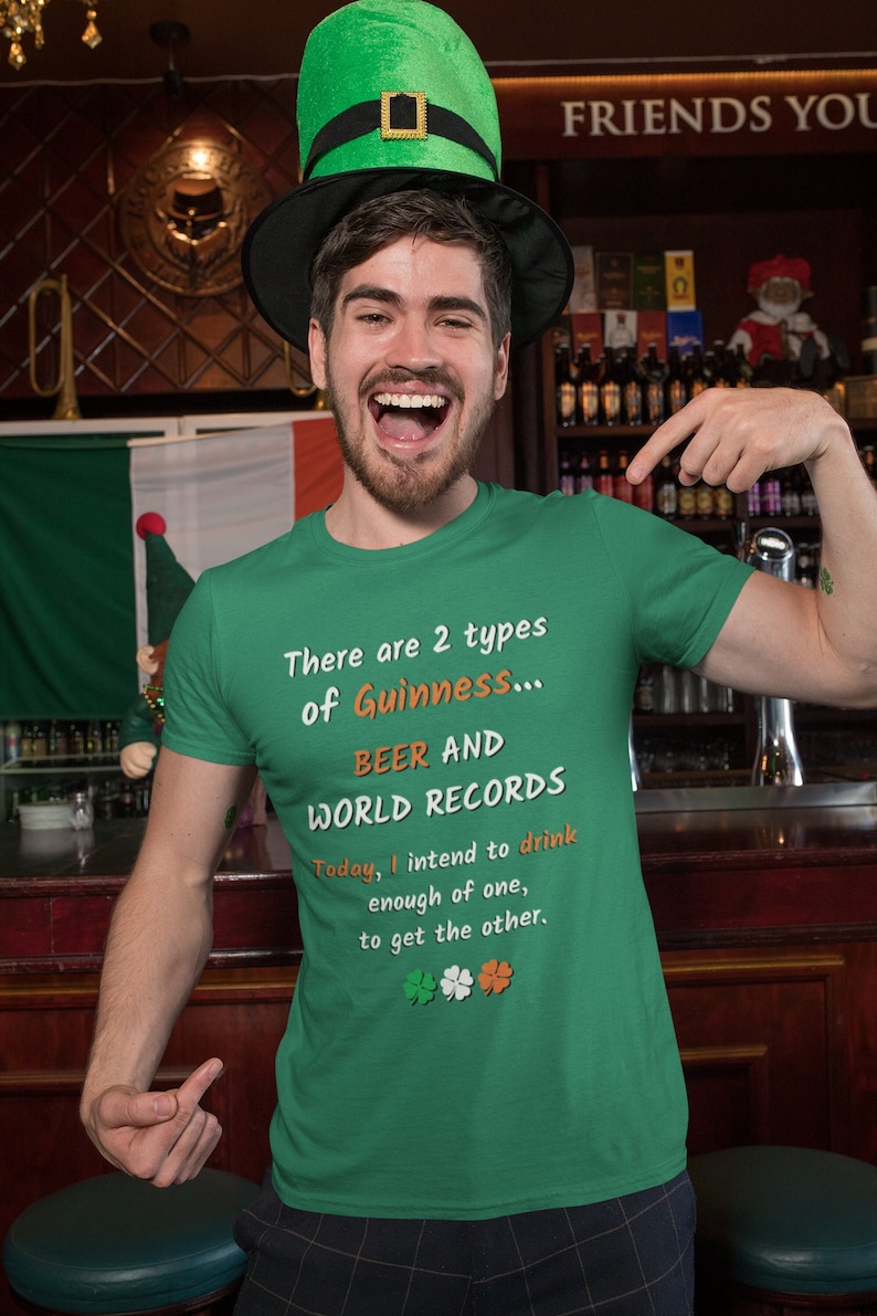 K&ouml;nnte beinhalten: Ein gr&uuml;nes T-Shirt mit einem wei&szlig;en und orangenen Design, auf dem steht "There are 2 types of Guinness... BEER AND WORLD RECORDS. Today, I intend to drink enough of one, to get the other." Das Shirt wird von einer Person mit einem gr&uuml;nen Hut und Bart getragen.