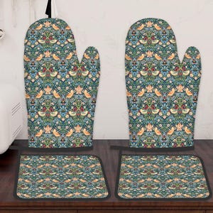 May include: A matching set of two oven gloves and two pot holders. The kitchen textiles display a repeating pattern of birds, flowers, and foliage in teal, orange, and red on a dark teal background. The pot holders are square.