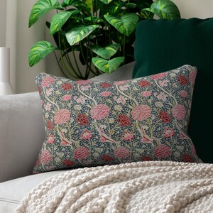 May include: A decorative throw pillow with a floral pattern featuring pink and red flowers on a dark blue background.