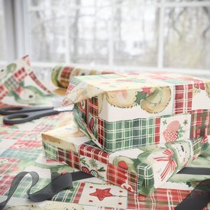 May include: Christmas gift boxes wrapped in festive paper with red, green, and white plaid and bear motifs. Scissors and a roll of wrapping paper are present, indicating the preparation of presents for the holiday season.