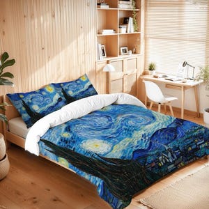 May include: A bed with a duvet cover and two pillowcases featuring a print of Van Gogh's "Starry Night" painting. The bedding has a blue, white, and yellow color scheme, with a swirling sky and a village scene. The bed is made of wood.