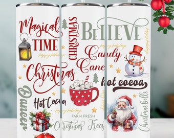 May include: Three white stainless steel tumblers with Christmas-themed designs. One features "Magical Time Christmas" with a lantern and gift. Another says "Believe Candy Cane" with a mug of cocoa. The third shows Santa and a snowman.