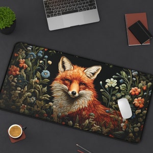Pode incluir: Um tapete de rato preto e branco com uma ilustração detalhada de uma raposa vermelha cercada por flores e folhas. A raposa está olhando diretamente para o observador.
