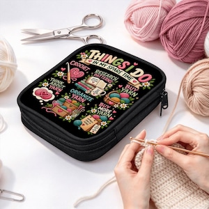 May include: A black zippered storage case featuring a colorful graphic with the text "THINGS I DO IN MY SPARE TIME" surrounded by illustrations of yarn, crochet hooks, and books, accompanied by silver scissors and various yarn balls.