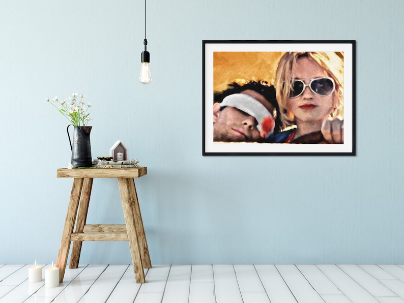 K&ouml;nnte beinhalten: Ein Schwarz-Wei&szlig;-Druck in einem schwarzen Rahmen, der ein Paar in einem Auto zeigt. Die Frau tr&auml;gt eine Sonnenbrille und der Mann hat ein Bandage &uuml;ber den Augen. Der Hintergrund ist ein verschwommenes Bild eines gelben und orangen Sonnenuntergangs.