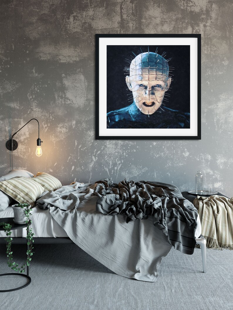 Pu&ograve; includere: Un poster incorniciato in nero con un'immagine in primo piano di un uomo con il viso ricoperto di punte. L'uomo guarda direttamente lo spettatore con un'espressione minacciosa. Il poster &egrave; appeso a un muro grigio sopra un letto con biancheria da letto grigia e bianca.