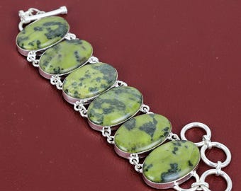 Pode incluir: Um bracelete de prata com fecho de correr apresenta seis pedras verdes ovais com manchas pretas.