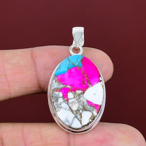 May include: Oval pendant with a vibrant, multicolored stone. The stone features a mix of bright pink, turquoise, white, and gray hues, set in a silver-toned metal frame. The pendant has a loop at the top for a chain.